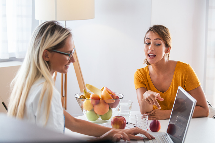 Professional nutritionist meeting a patient in the office. young smiling female nutritionist in the consultation room. Nutritionist desk with healthy fruit and measuring tape.