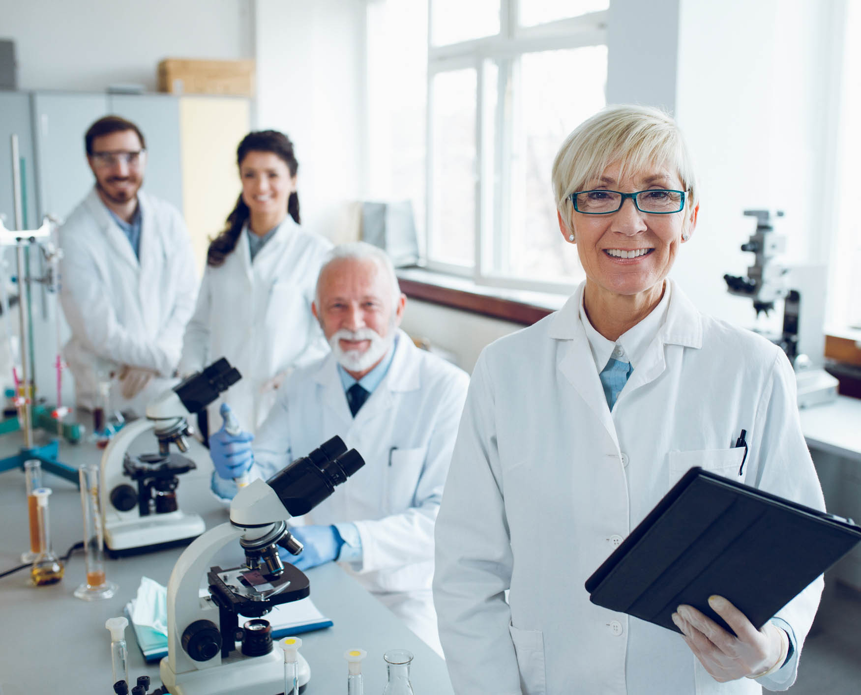 Smiling senior scientist with her colleagues in laboratory